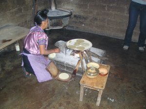 A Mexican lady making tortillas in a press